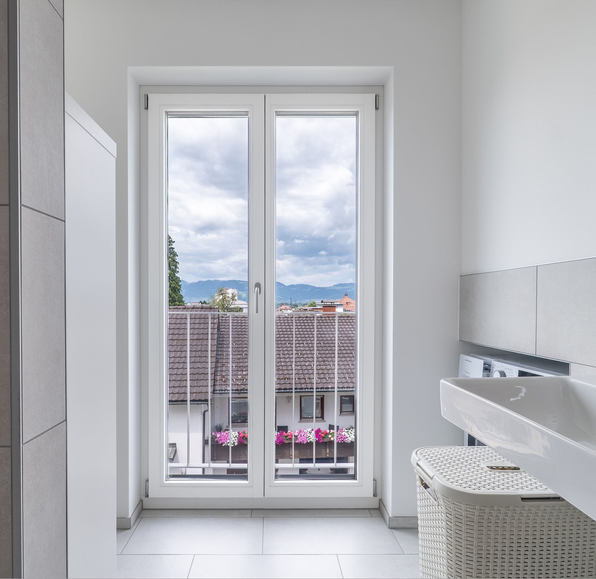 Kleine Wohnanlage mit weißen Balkontüren und im obersten Stock Hebe-Schiebetüren.